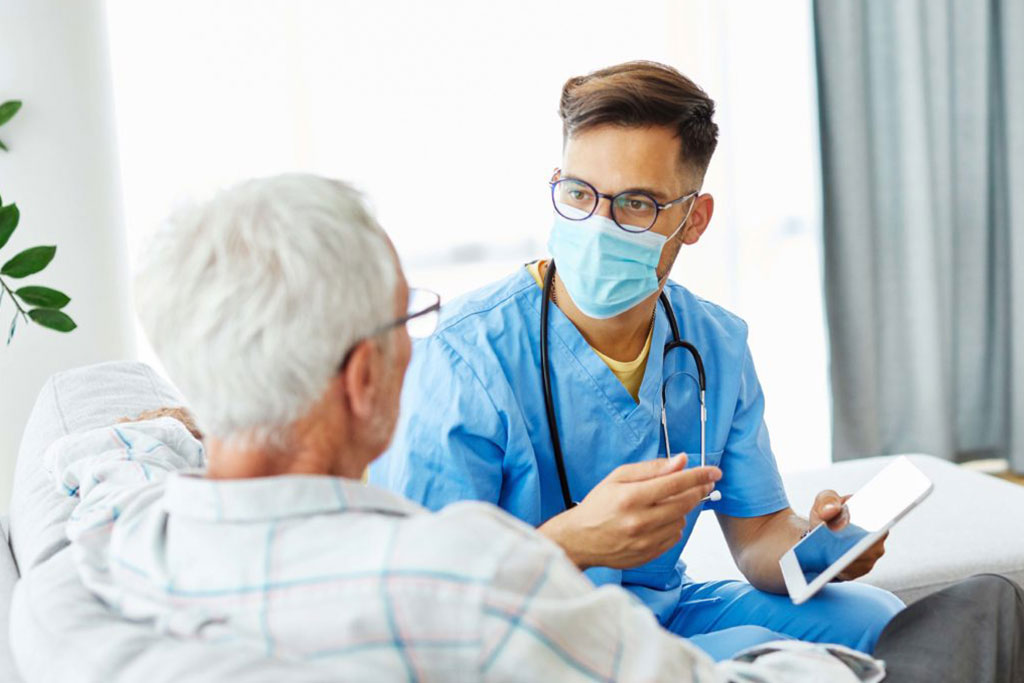 Male nurse with mask talking to elderly man at home